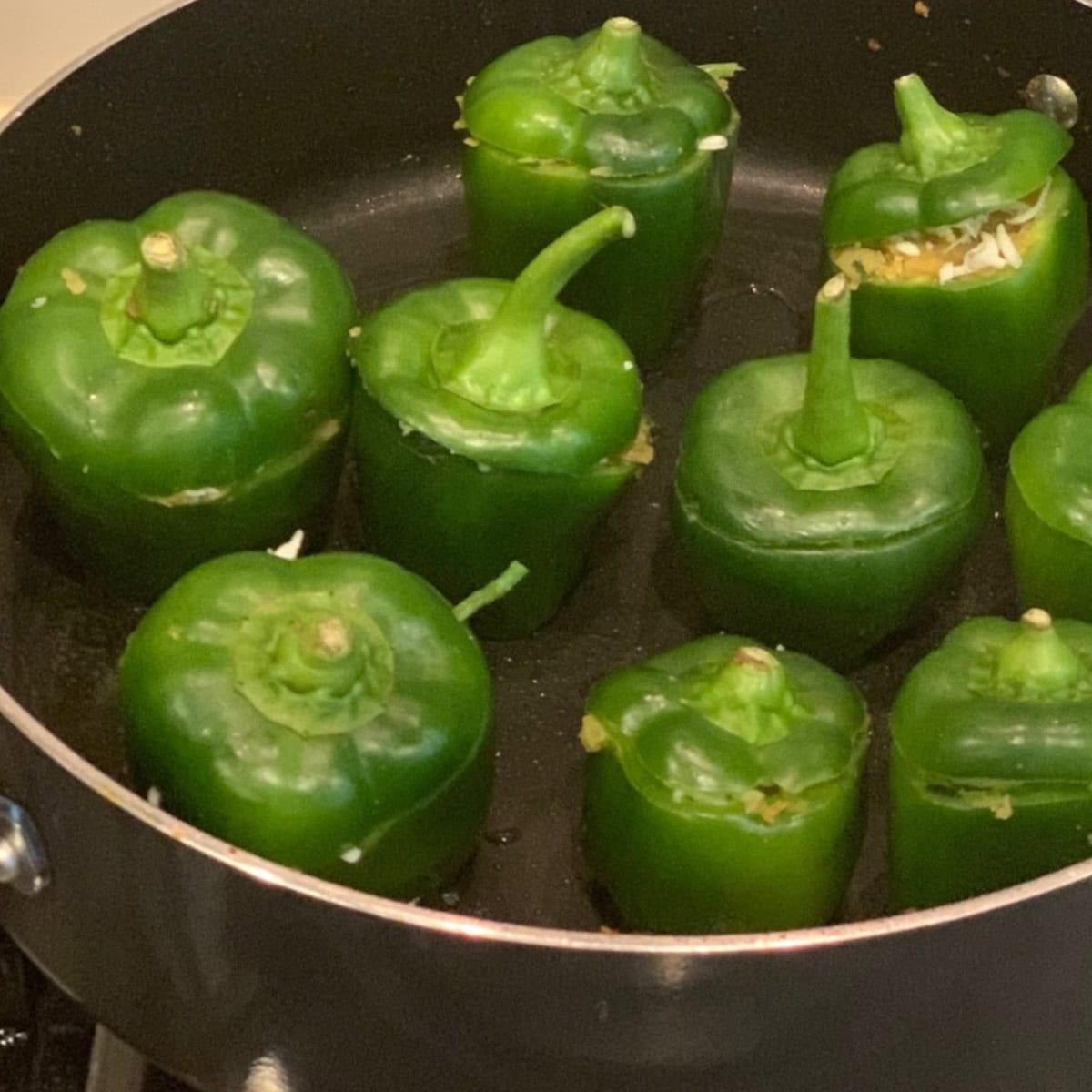 stuffed bell peppers in a black pan ready to be cooked.