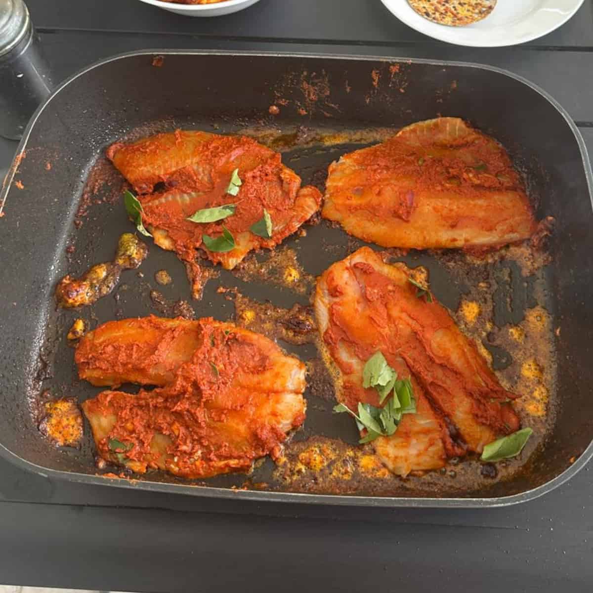 pan-fried Tilapia being cooked in a black electric fryer.