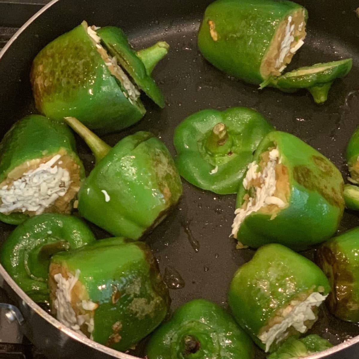 stuffed bell pepper being cooked in a black pan.
