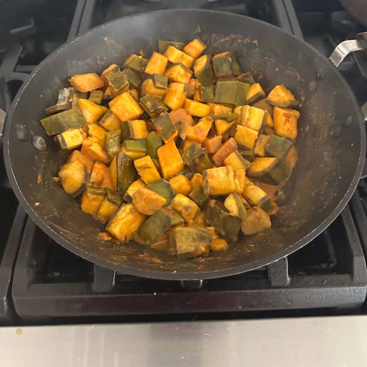 cooking plantain and yam with spices in a black wok.