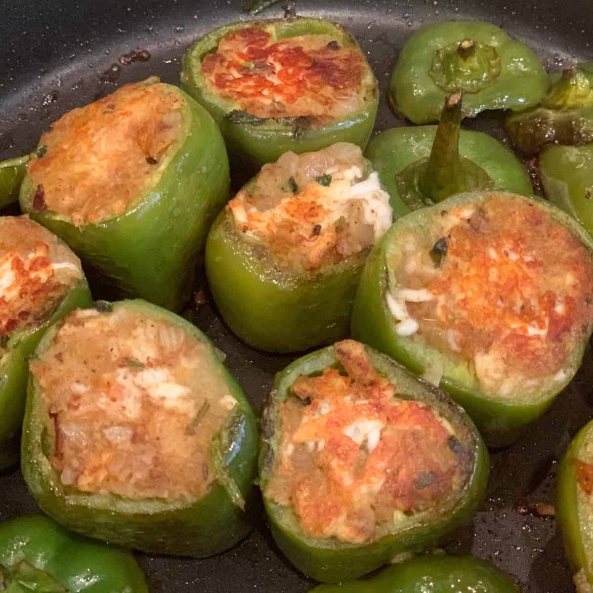 stuffed bell pepper being cooked in a black pan.