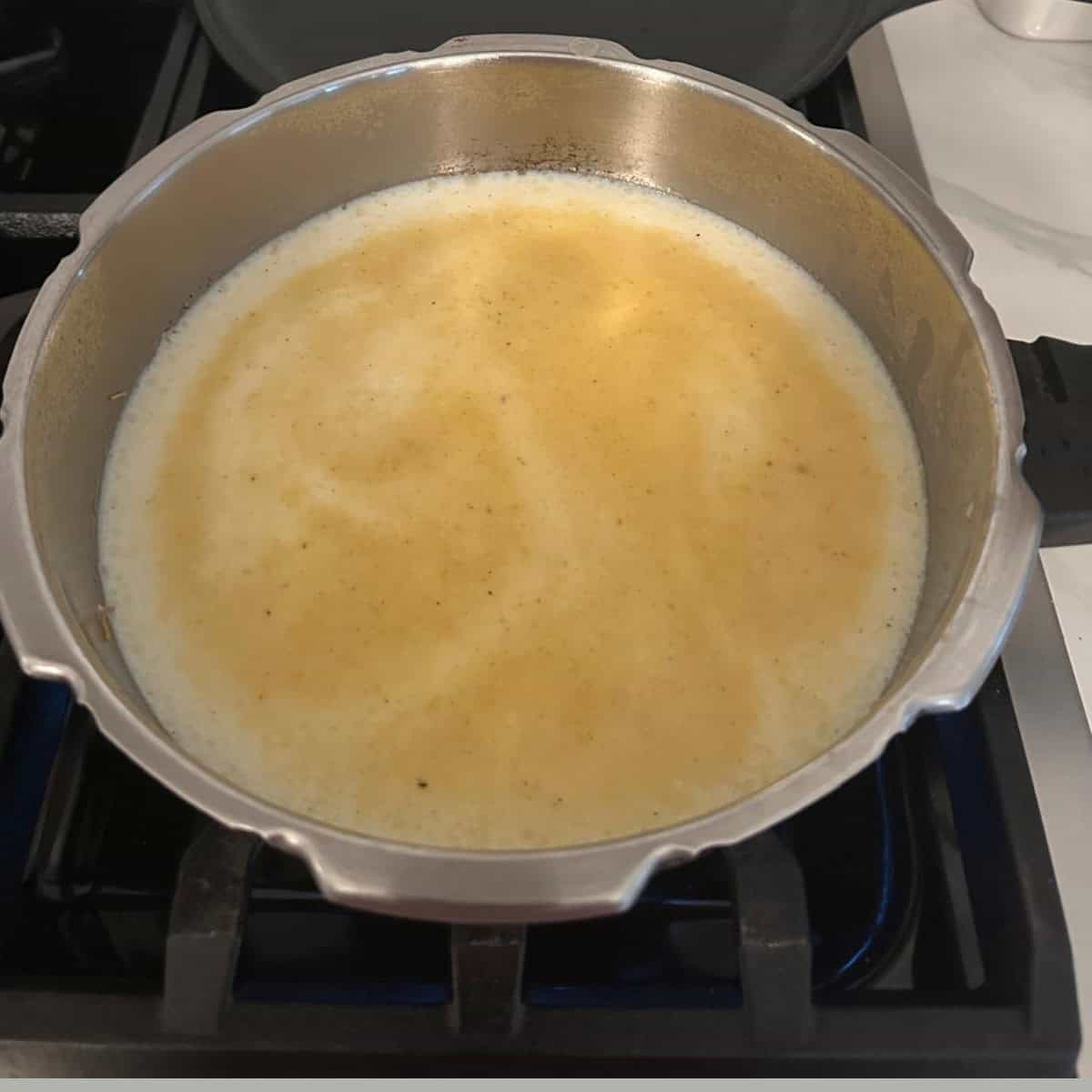 Adding milk to the payasam cooking in a cooker.