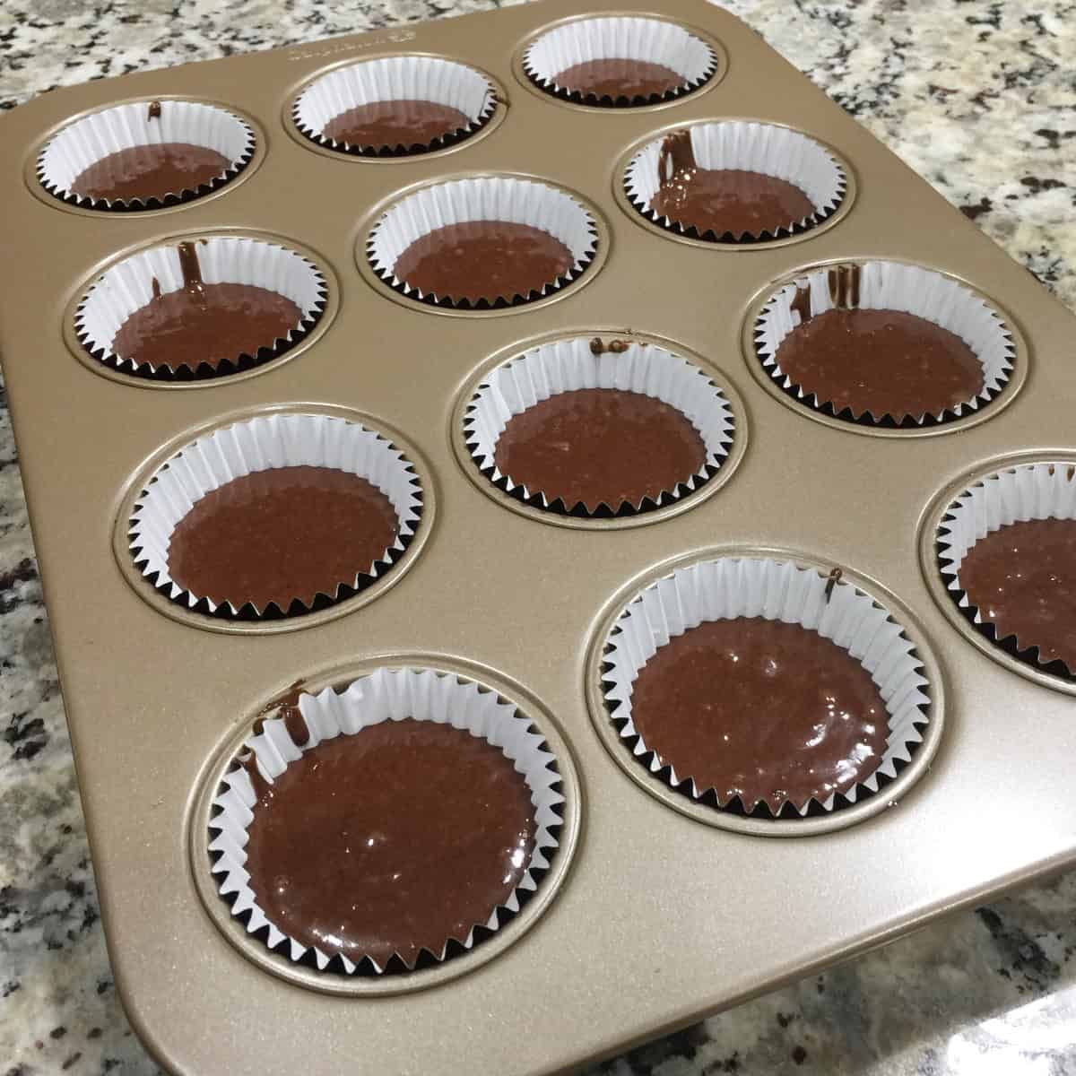 chocolate cupcakes ready to be baked in a cupcake tray.