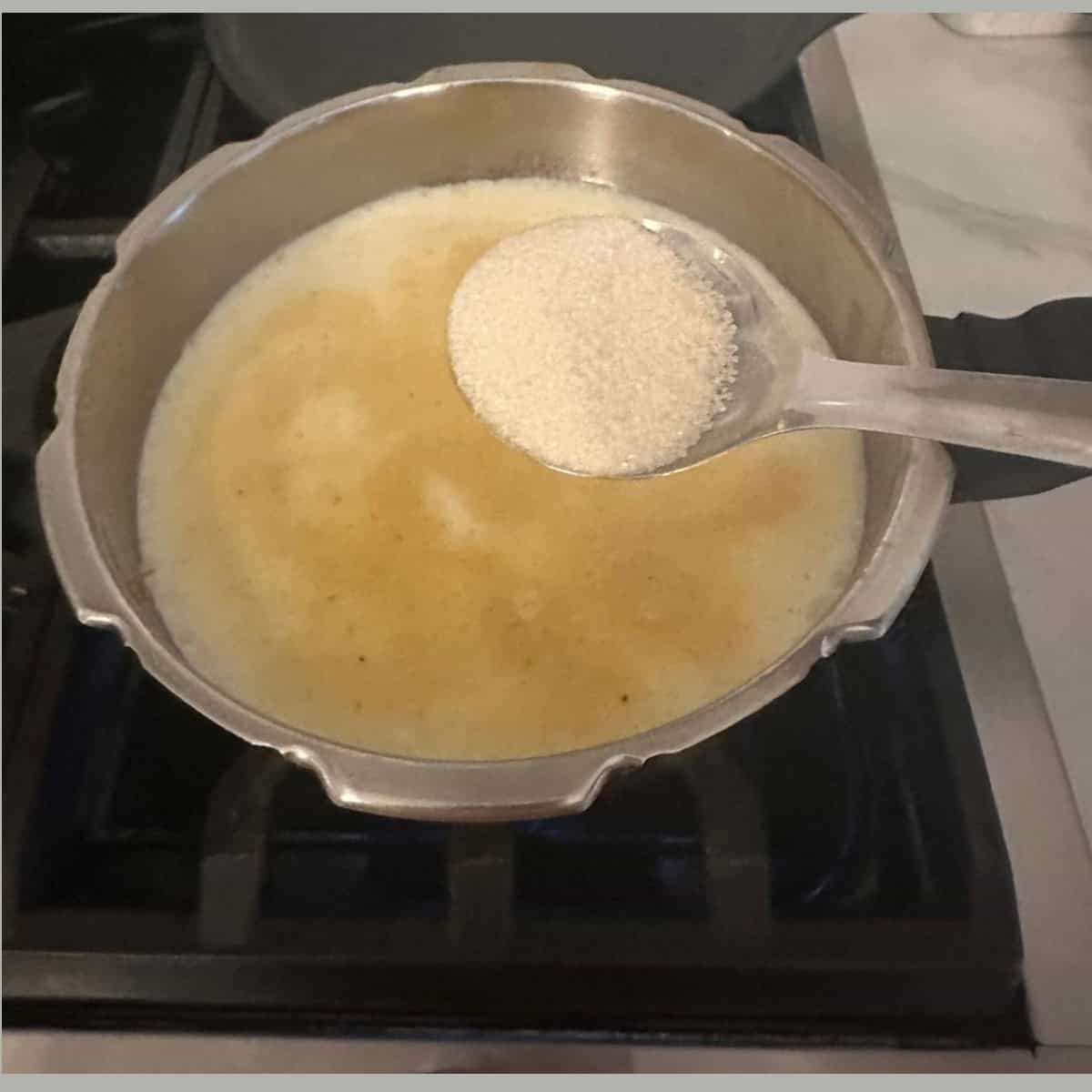 Adding sugar to the payasam cooking in a cooker.