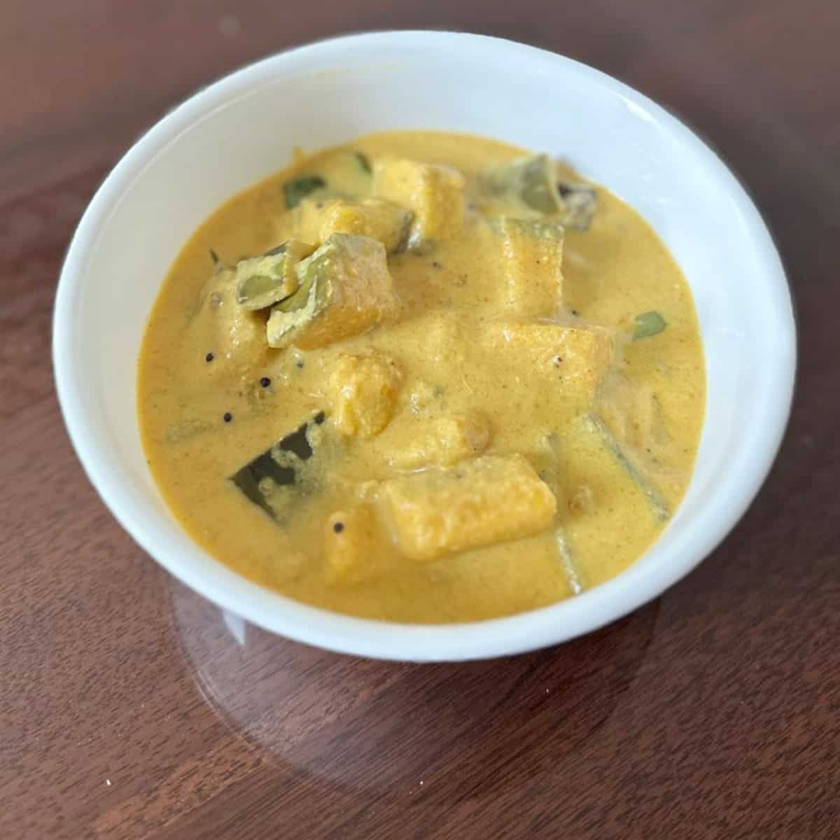 Kaalan served in a white bowl on a wooden board.