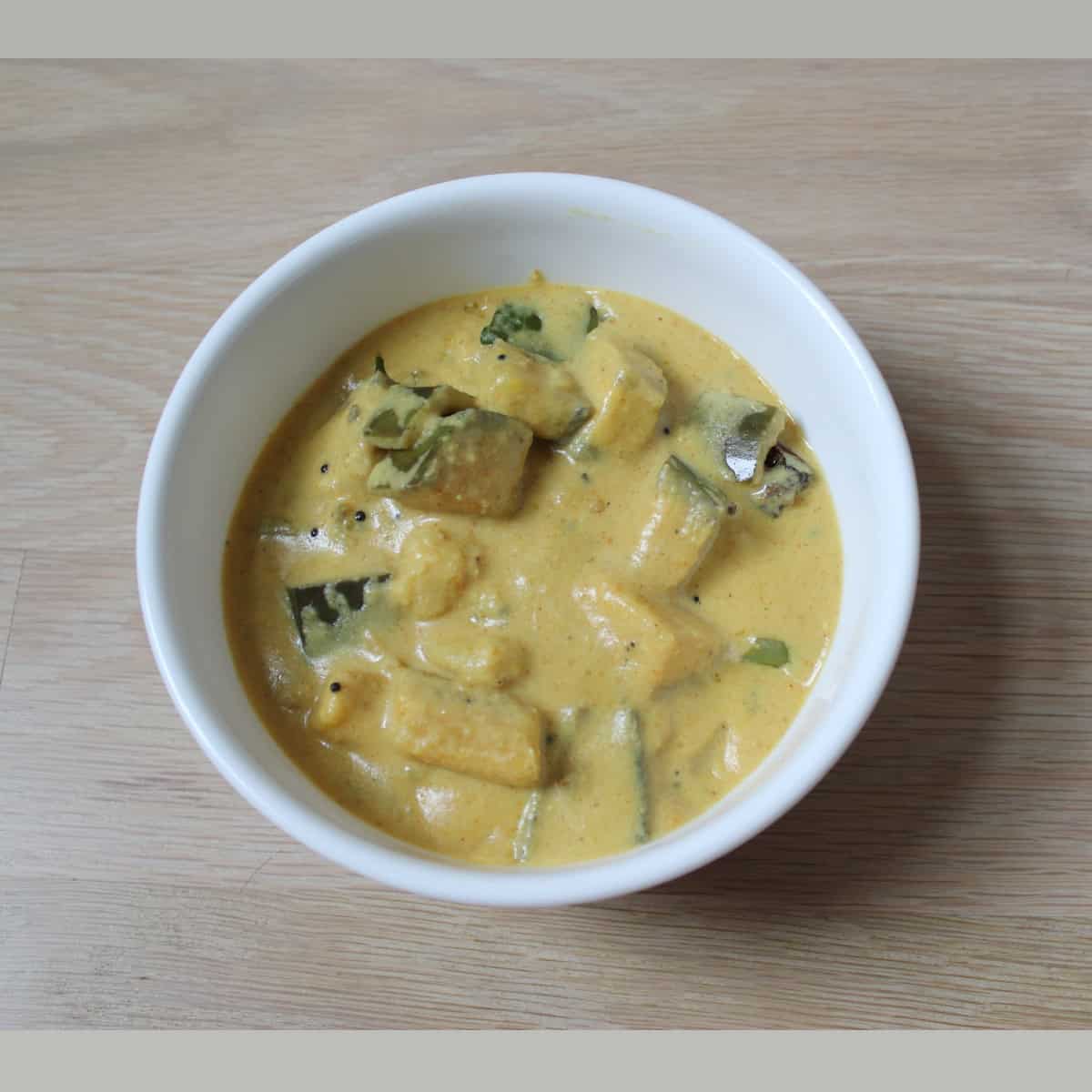 Kaalan served in a white bowl on a wooden board.