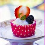 Baked mini cheesecakes with whipped cream and berries in a dessert bowl.