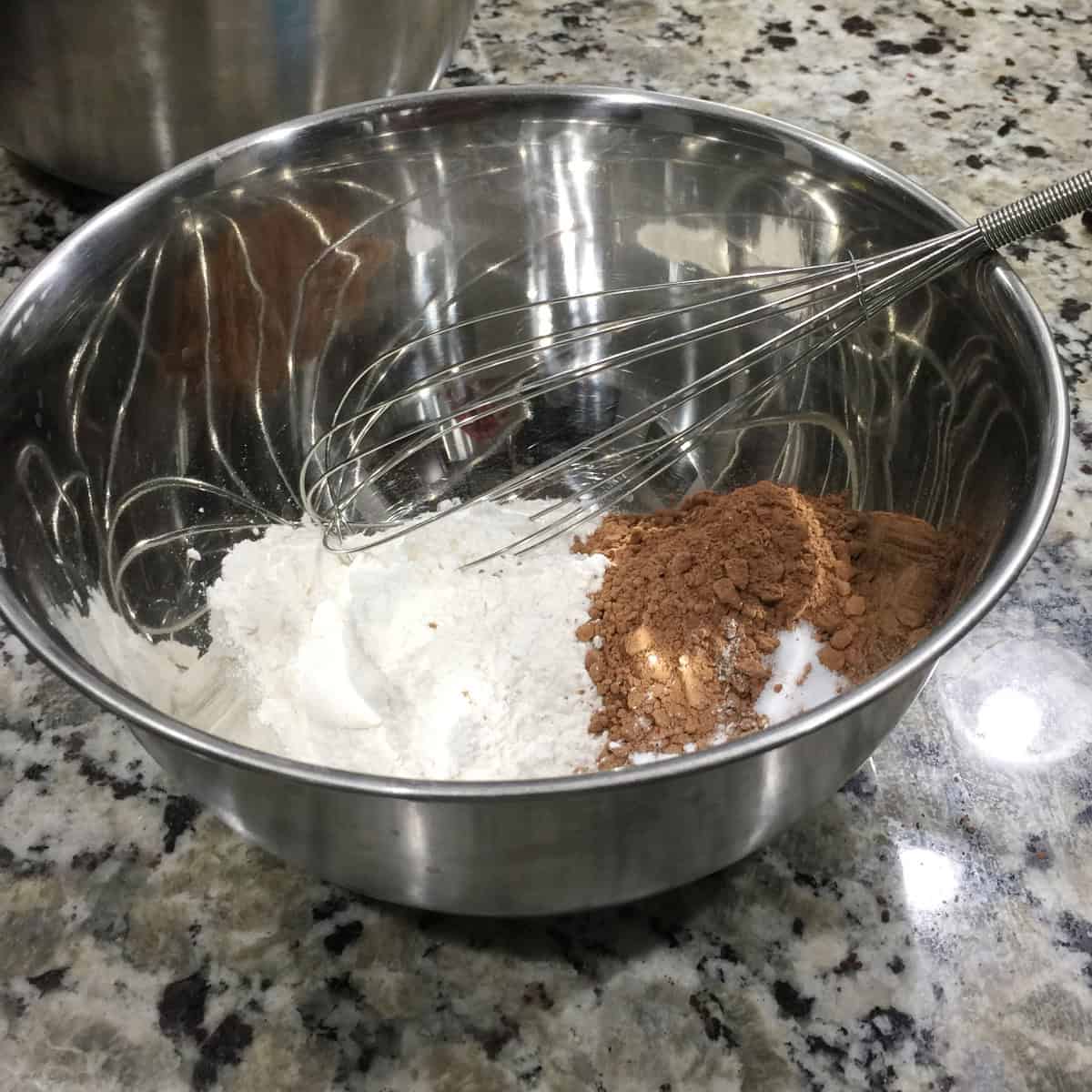 dry ingredients to make chocolate cupcakes in a steel bowl with a whisk.