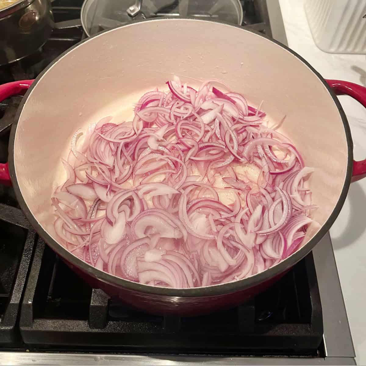 onions cooking in a cast iron pot to make crab masala curry.