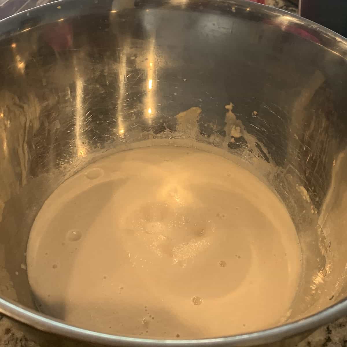 mixing bloomed yeast with bread flour in a steel bowl to make vegetarian pizza.