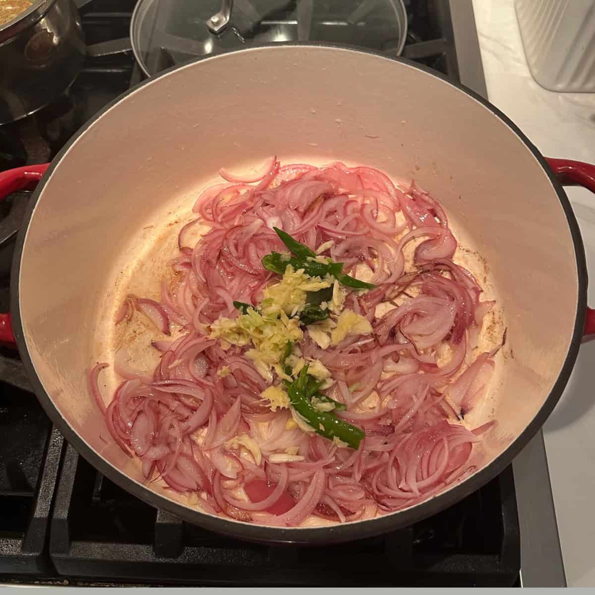 crushed garlic and ginger with green chilies added to onions in a cast iron pot to make crab masala curry.
