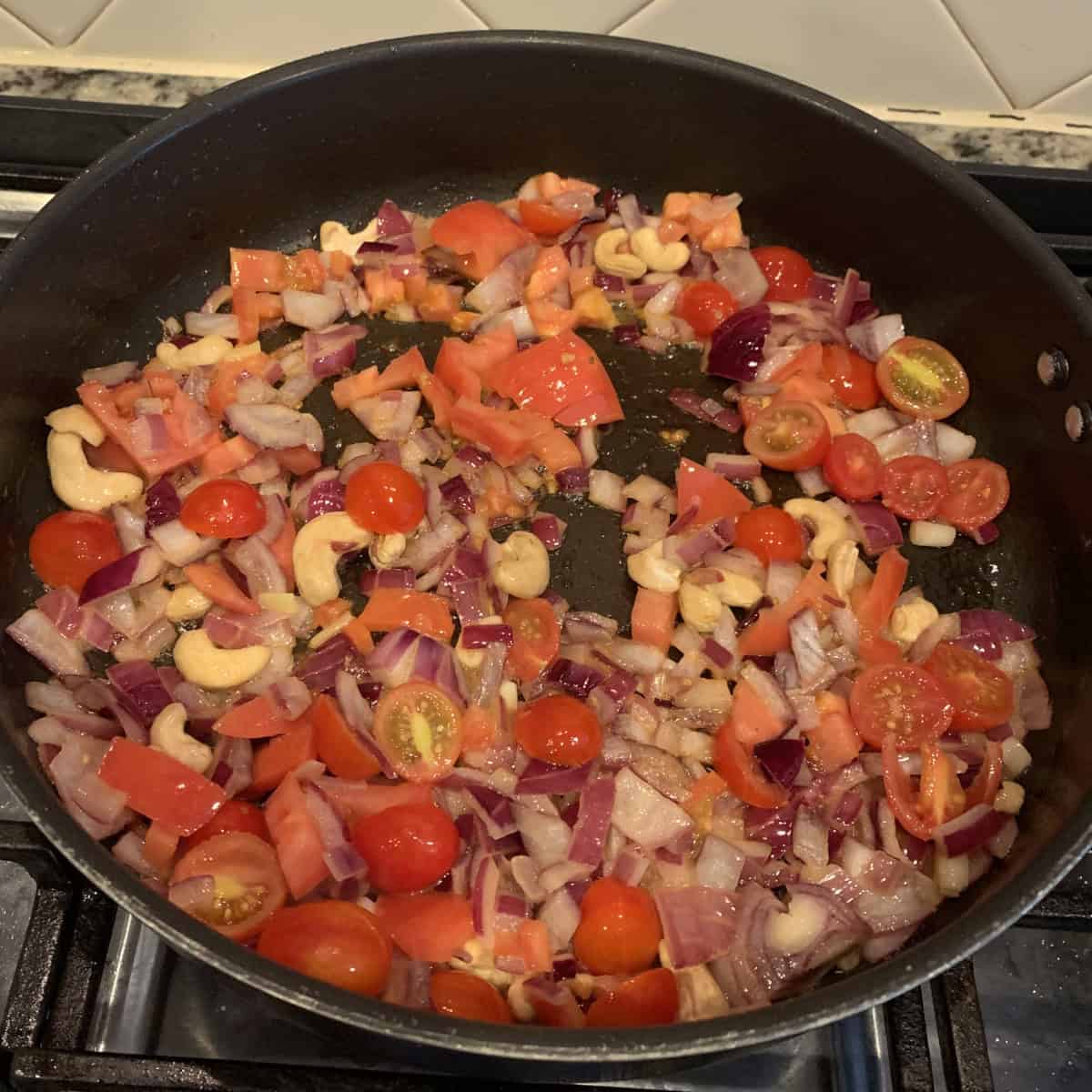 Paneer Tikka Masala. gravy preparation with tomatoes onions in a black pan.