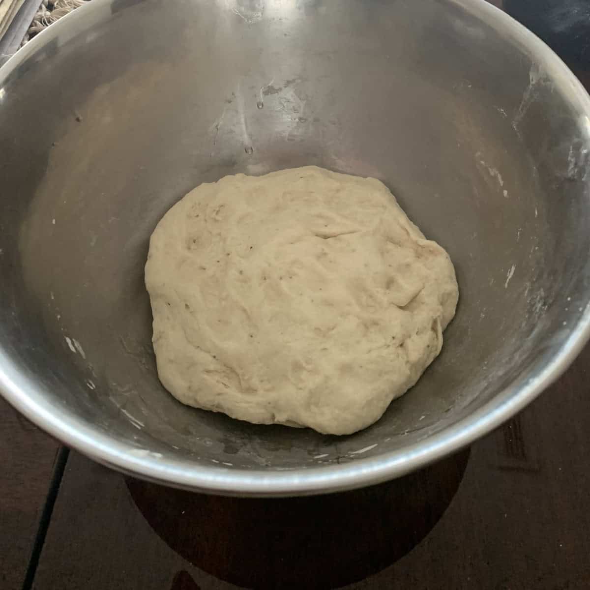 vegetarian pizza dough in a silver bowl ready for fermentation.