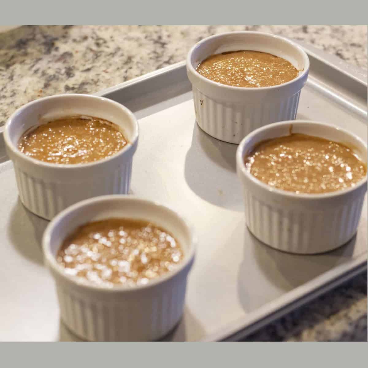 Hot Choco Lava Cake batter in four white ramekins going to the oven.