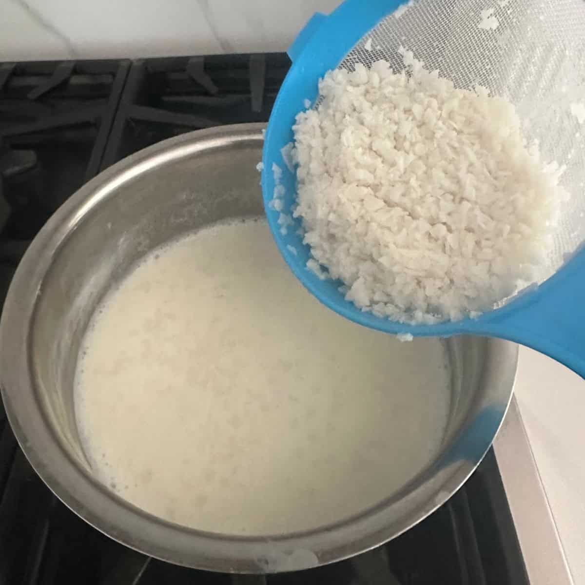 soaked ada being added to sweetened milk in a bowl.