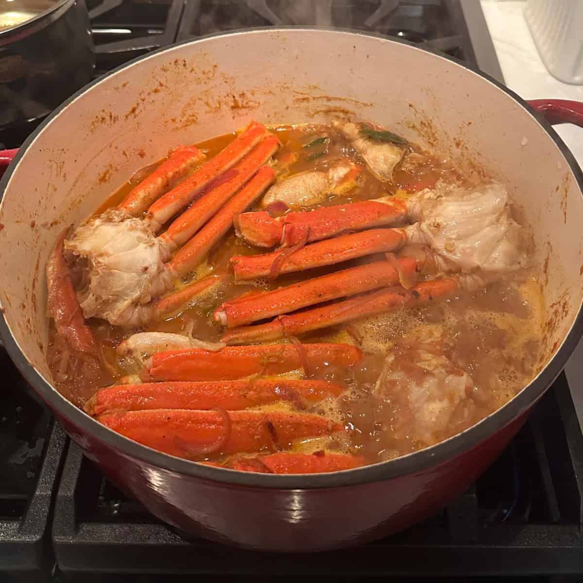 cleaned crabs added to curry preparation in a cast iron pot.