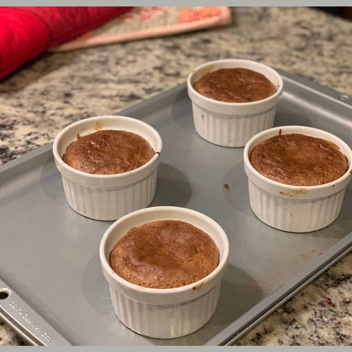 Hot Choco Lava Cake baked and ready in ramekins on a gray baking tray.