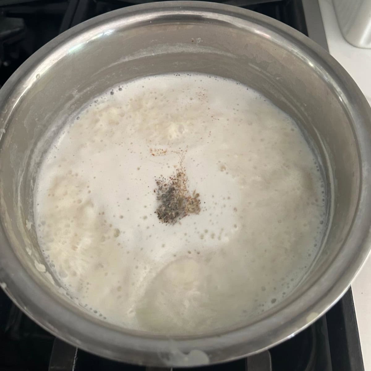 powdered cardamom added to palada payasam in a steel bowl.
