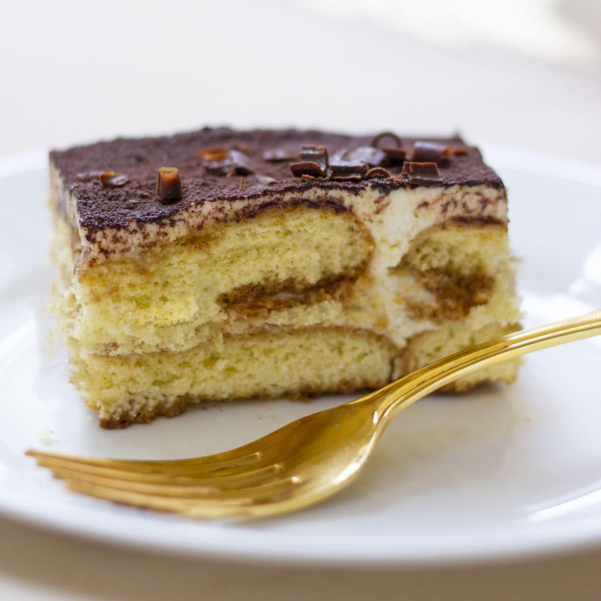 Tiramisu recipe with eggs served in a white dessert plate with a golden fork.