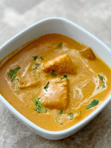 Paneer Tikka Masala Restaurant Style in a white bowl garnished with coriander leaves and cream.