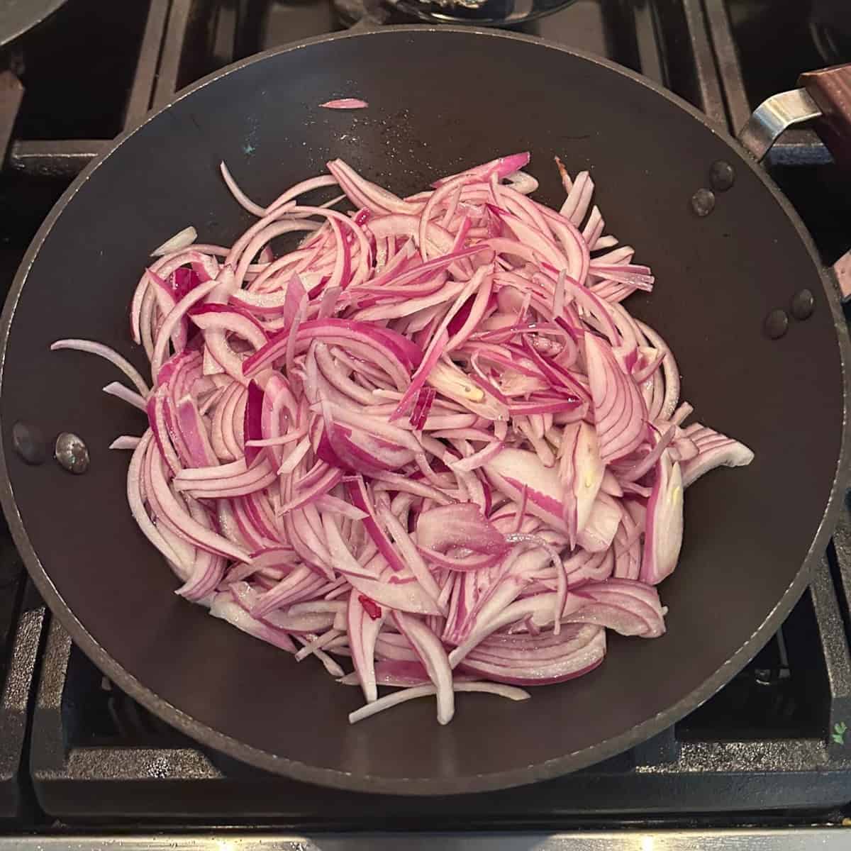 onions being sauteed in a black wok.