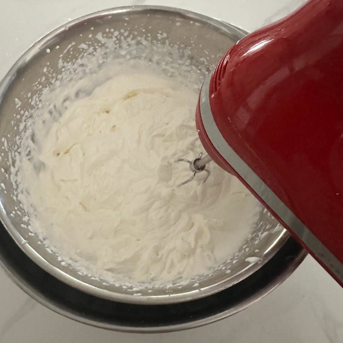 Cream being whipped with a hand held mixer.