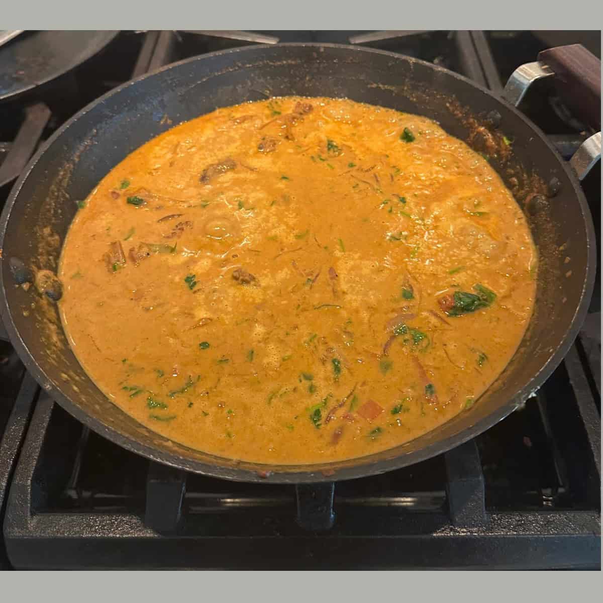 Curry chicken with coconut milk in a black wok.