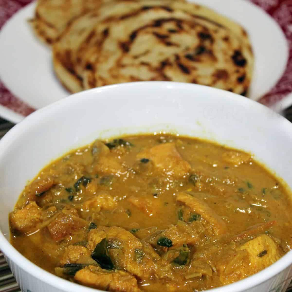 Curry chicken with coconut milk in a white bowl.