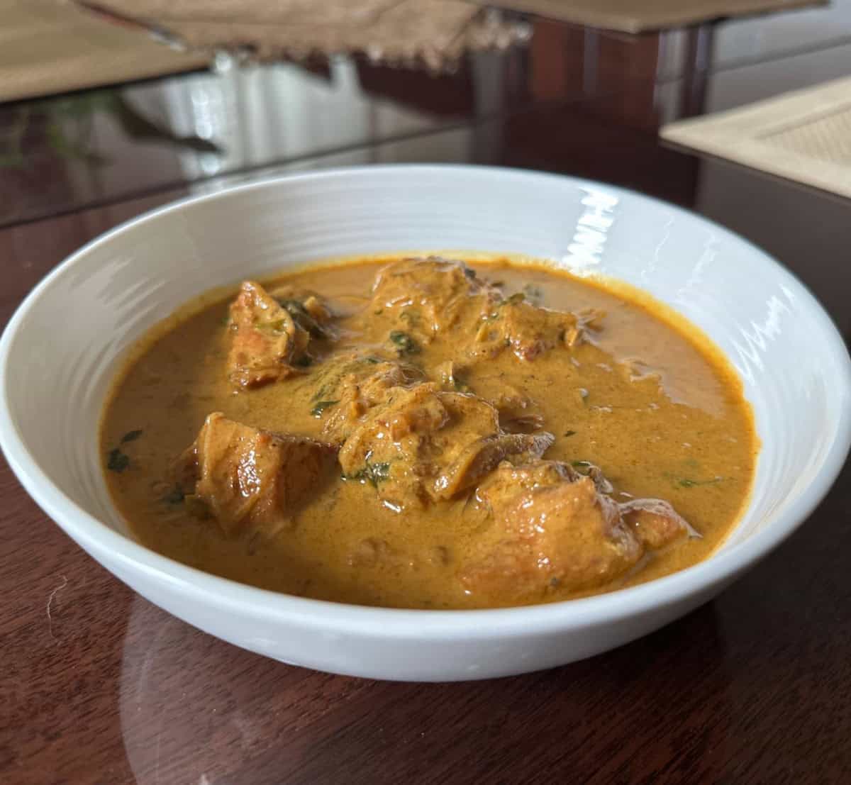 Curry chicken with coconut milk in a white bowl.