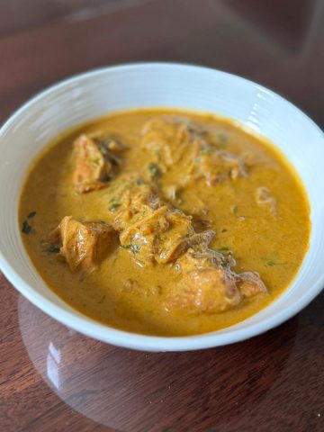 Curry chicken with coconut milk in a white bowl.