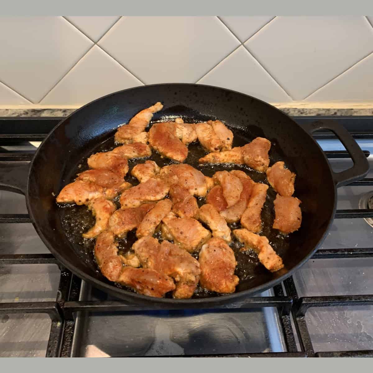 chicken sauteed on a black skillet.