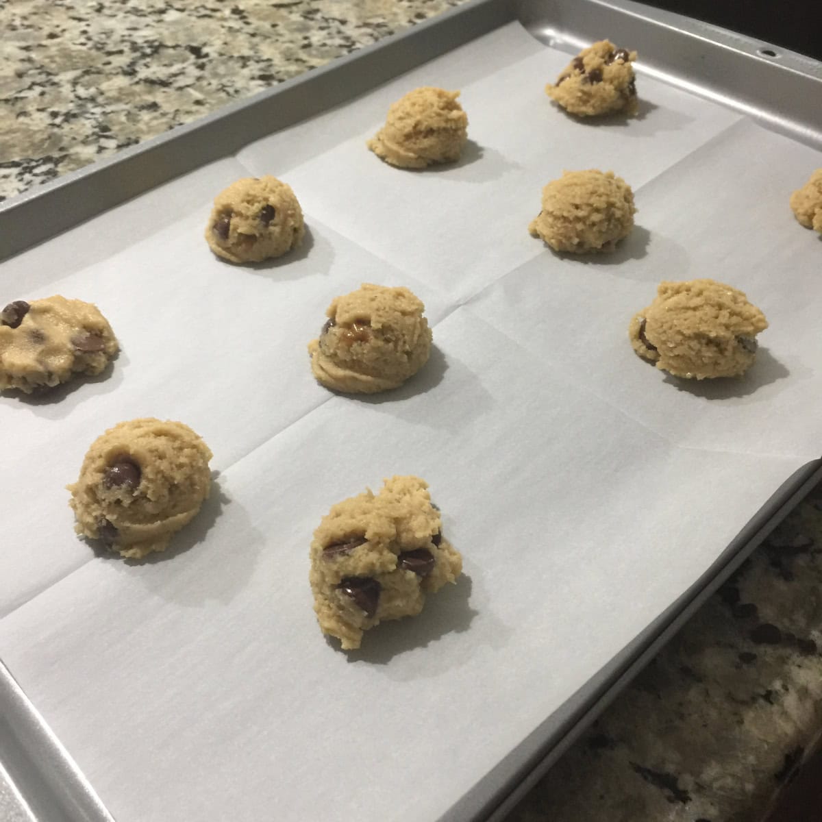 Almond flour chocolate chip cookies batter scooped on to baking tray lined with parchment paper.
