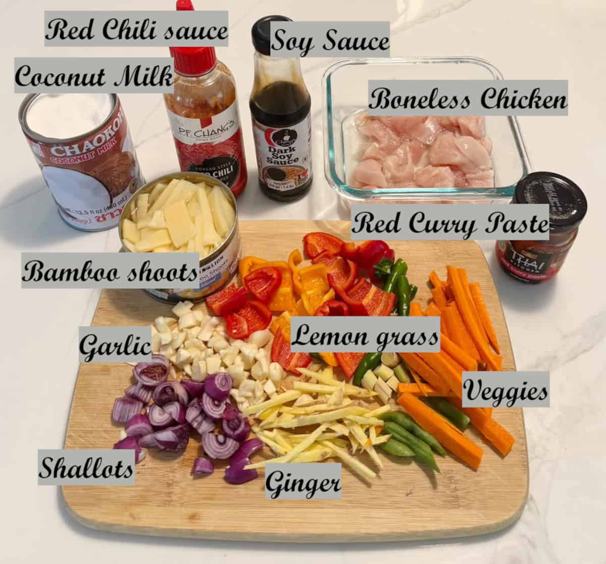 Ingredients to make Thai red curry with names displayed on a wooden board.
