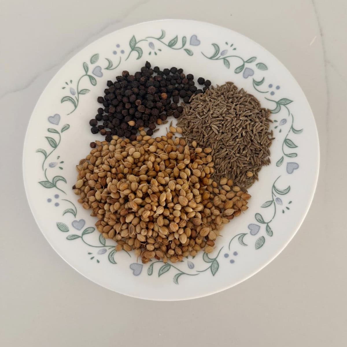 whole spices for rasam in a white plate.