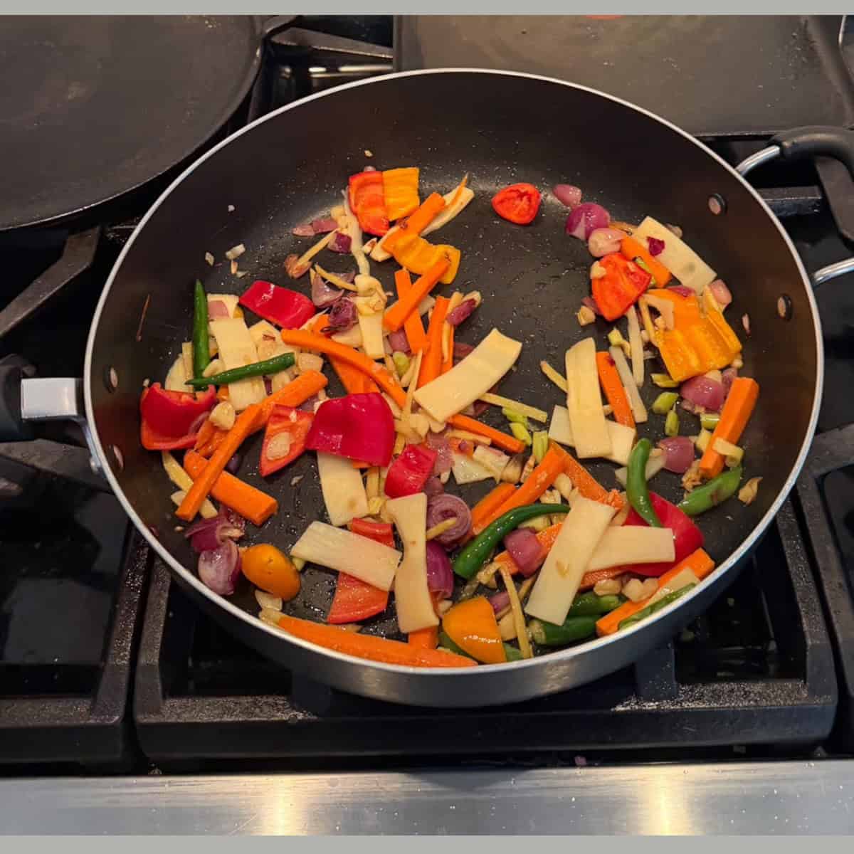 veggies sauteed in a black pan.