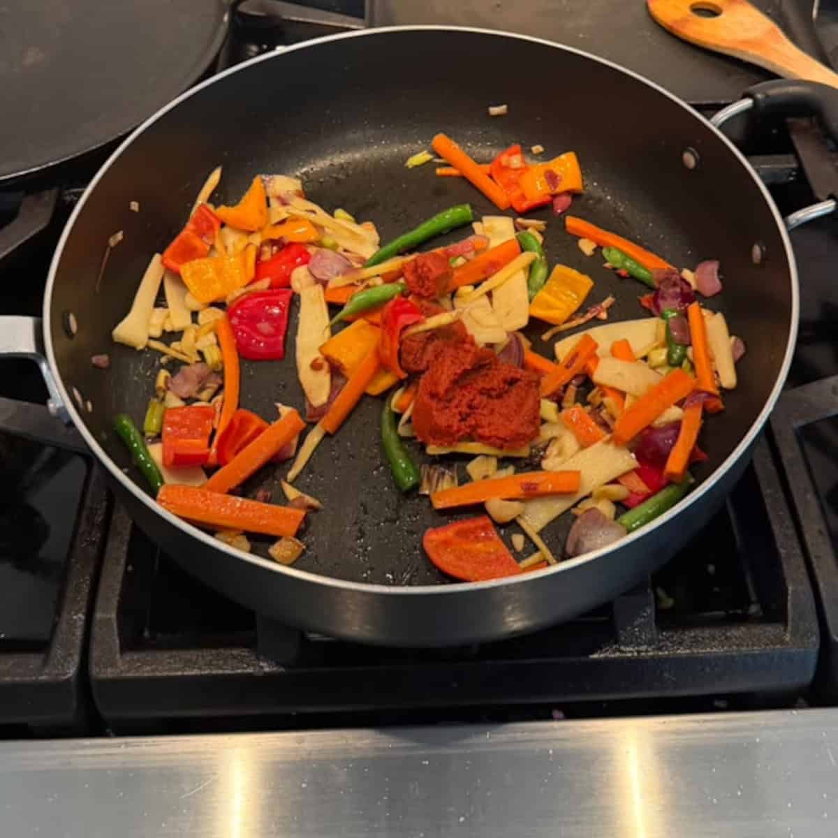 red curry paste with veggies sauteed in a black pan.