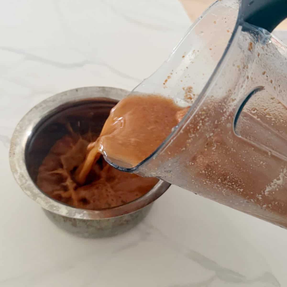 Ground pate for rasam being poured int a steel bowl.
