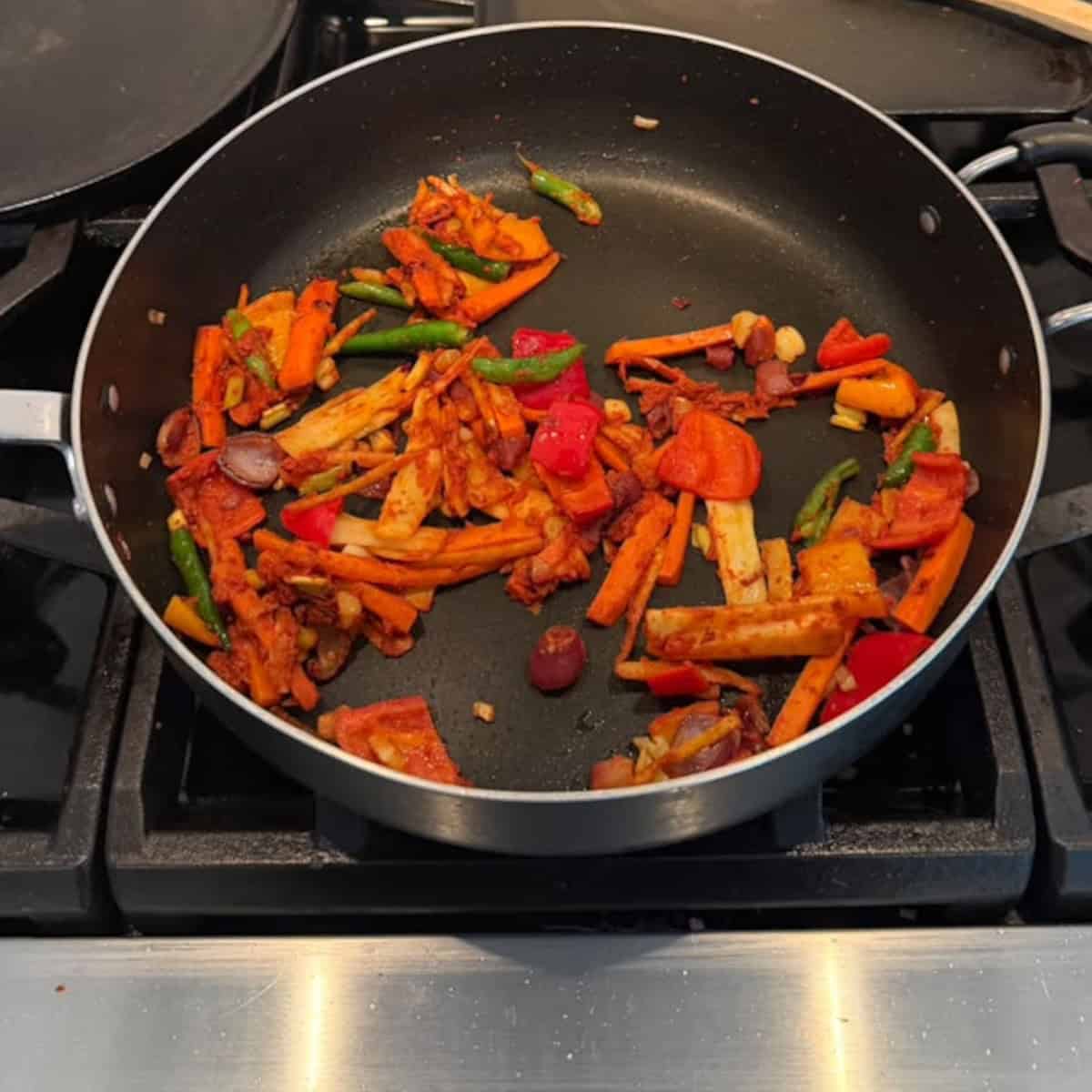 veggies sauteed in a black pan.