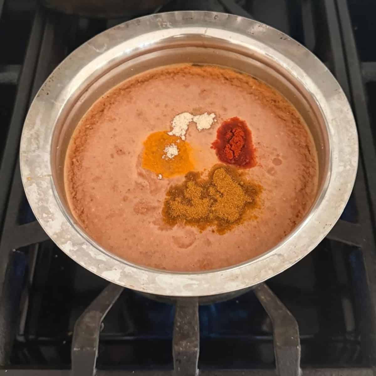 Rasam with spices ready to boil in a steel container.