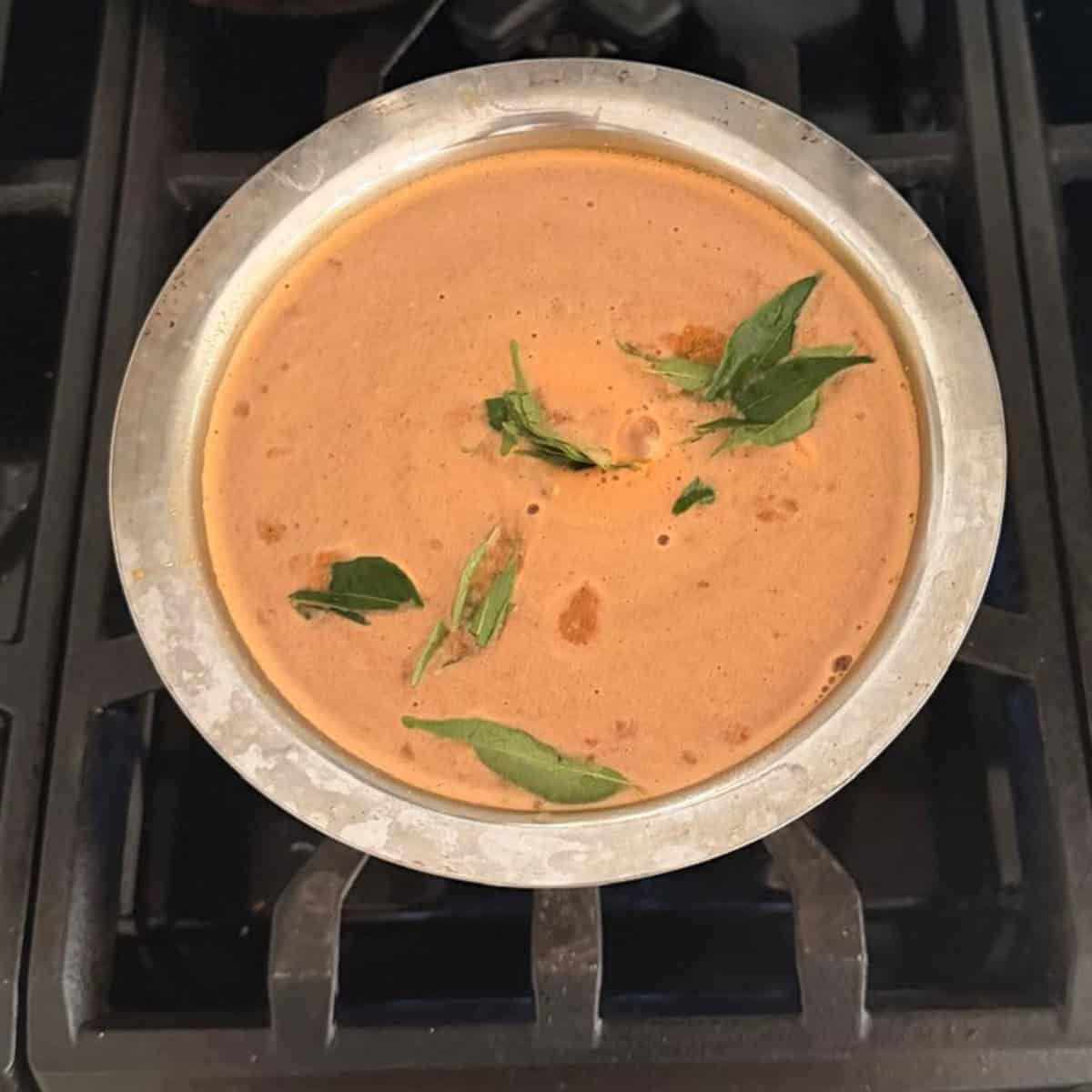 Rasam ready to boil in a steel container.