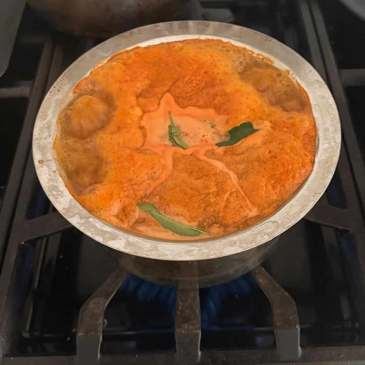 Rasam boiling in a steel container.