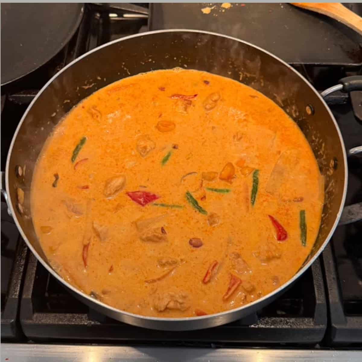 Thai red curry simmering in a black pan.