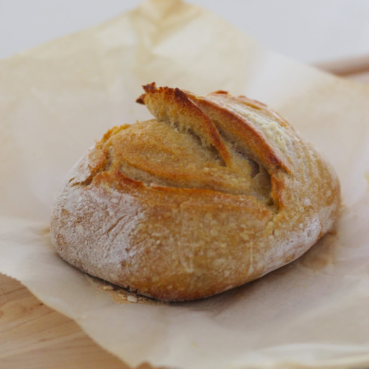 Freshly baked Beginner Sourdough Bread on a parchment paper on a wooden board.