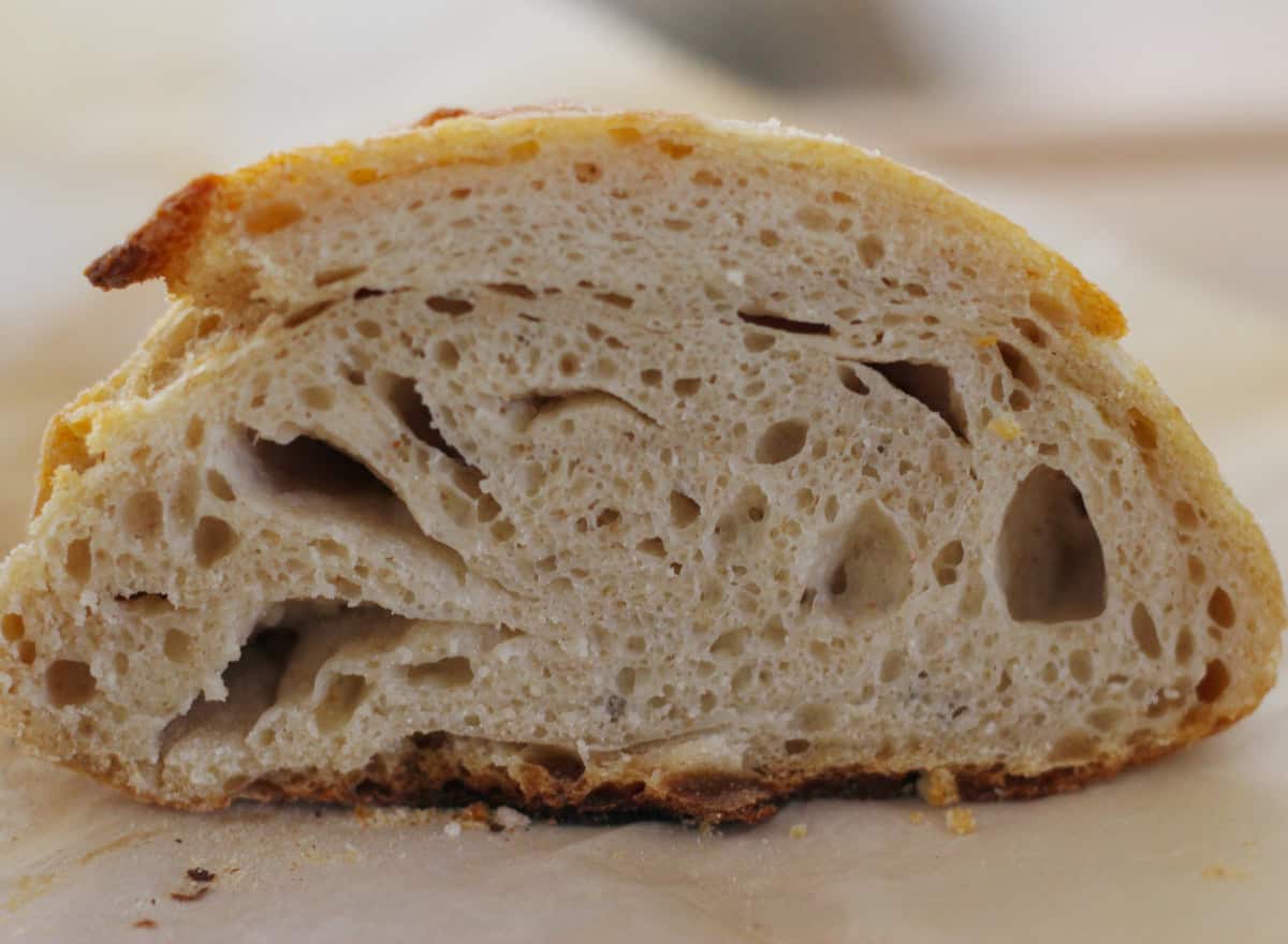 Sourdough Bread sliced to show the pores on a parchment paper on a wooden board.